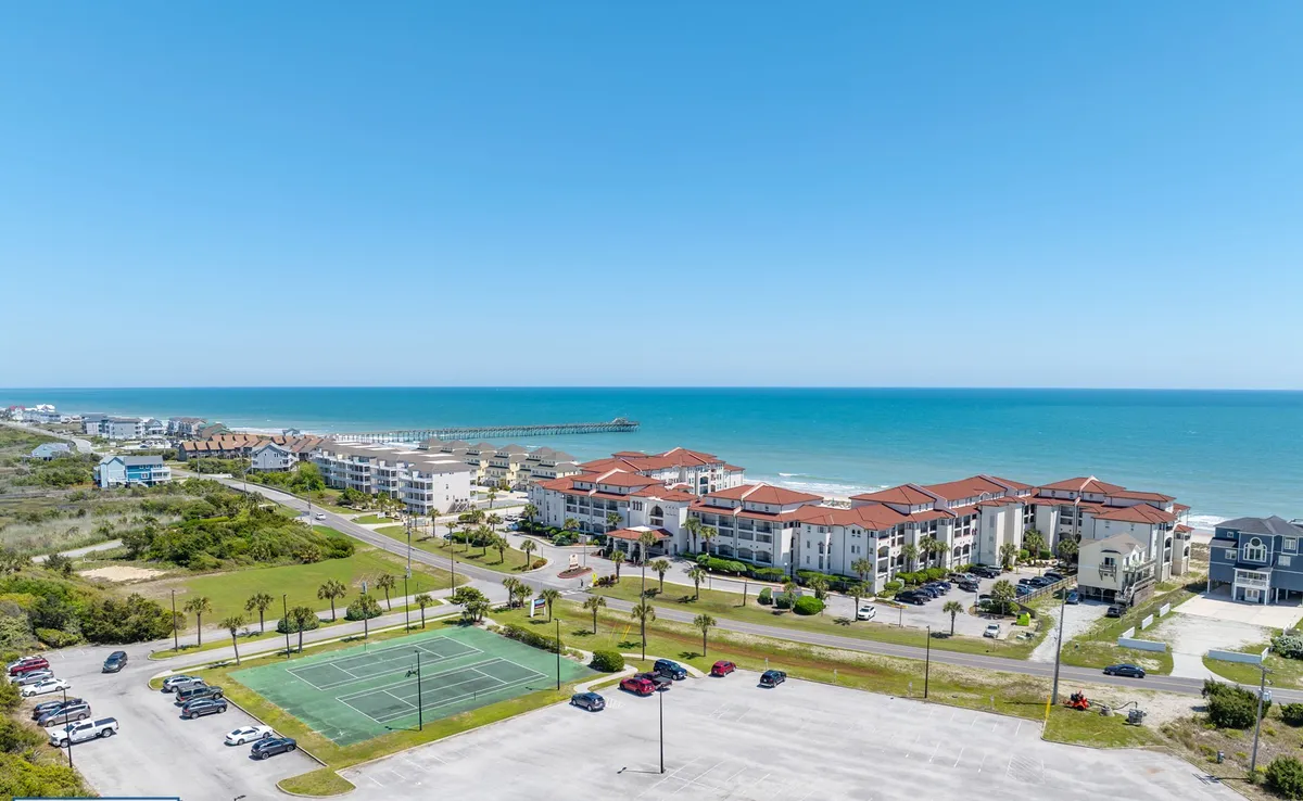 This image captures a sweeping ocean view with a visible pier in the distance, flanked by palm trees and bordered by residential buildings. The tranquil shoreline and the iconic pier evoke the quintessential seaside experience described in the section.