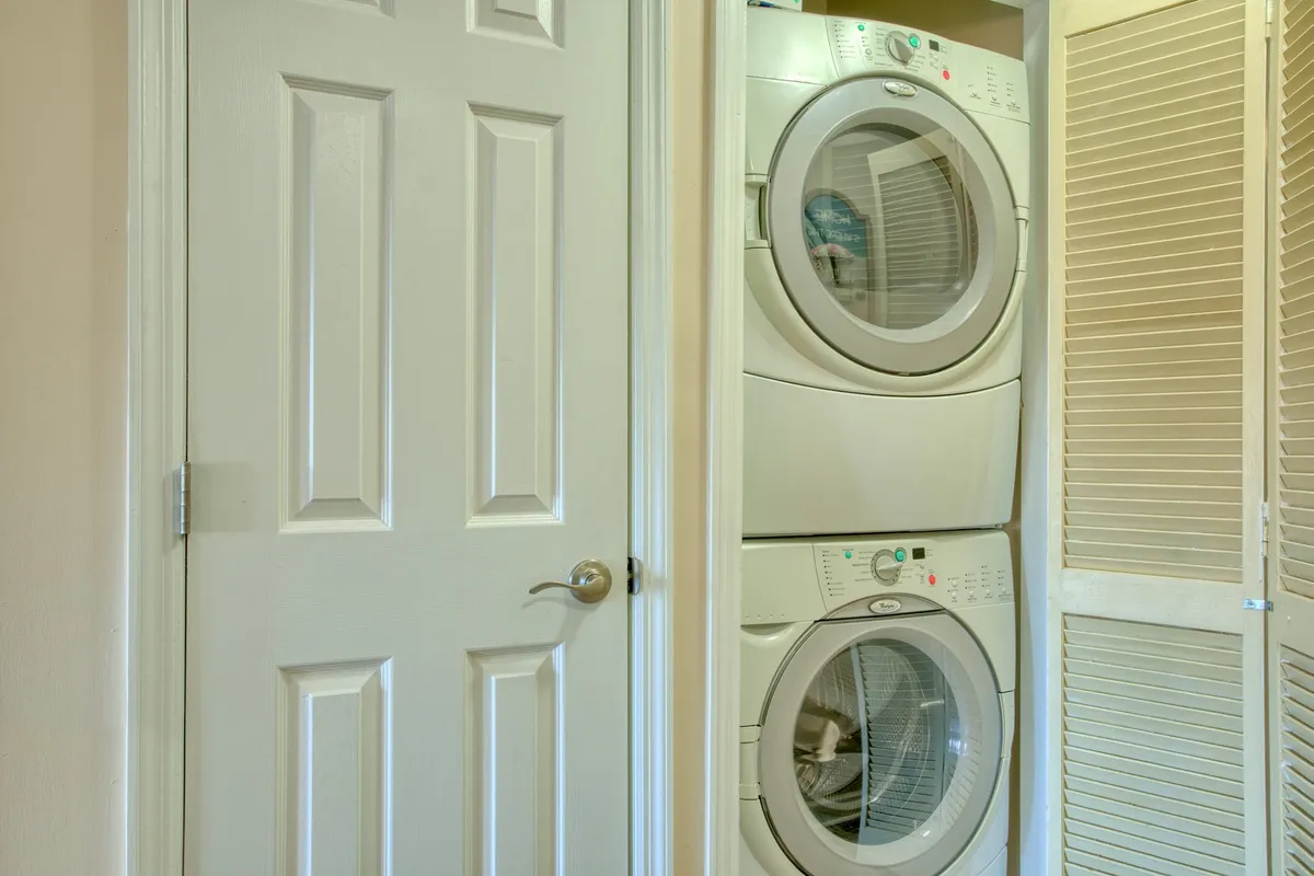 A practical laundry area with a stacked full-size washer and dryer tucked behind louvered doors, conveying convenience and thoughtful amenities for guests.